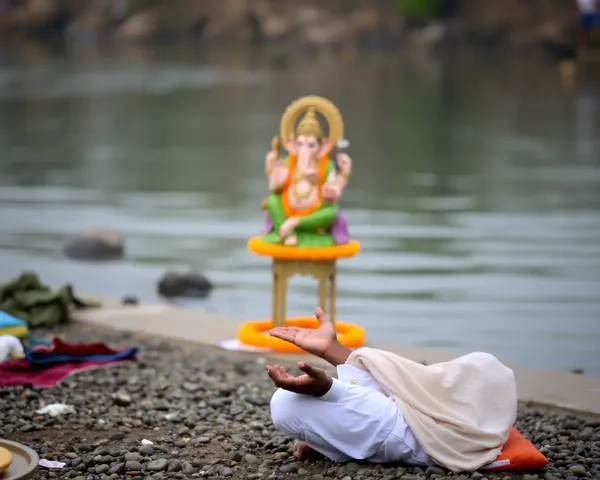 Devotee Meditates by River with Ganesh Idol in Background